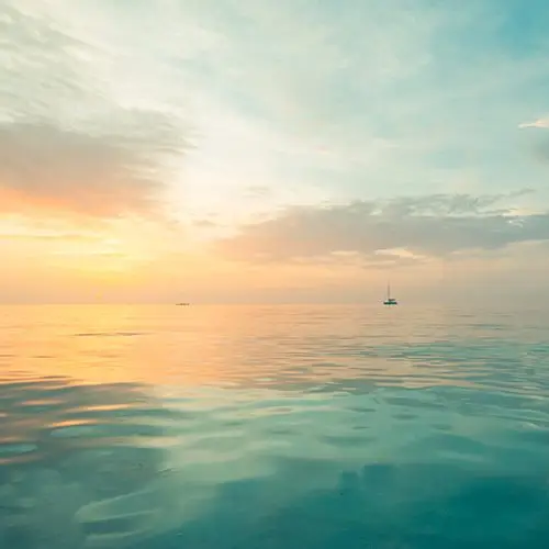 Look out on a calm blue sea with boat in the distance at sun rise
